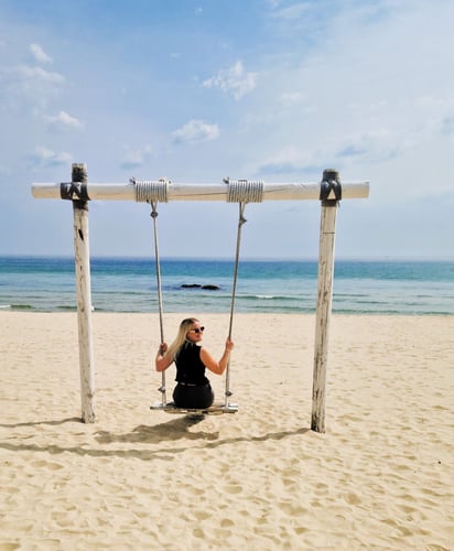 Katie auf einer Schaukel am Strand bei der Tour durch Südkorea
