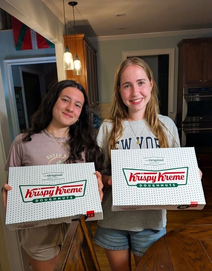 Zwei Austauschschülerinnen in den USA halten Boxen mit Donuts in den Händen